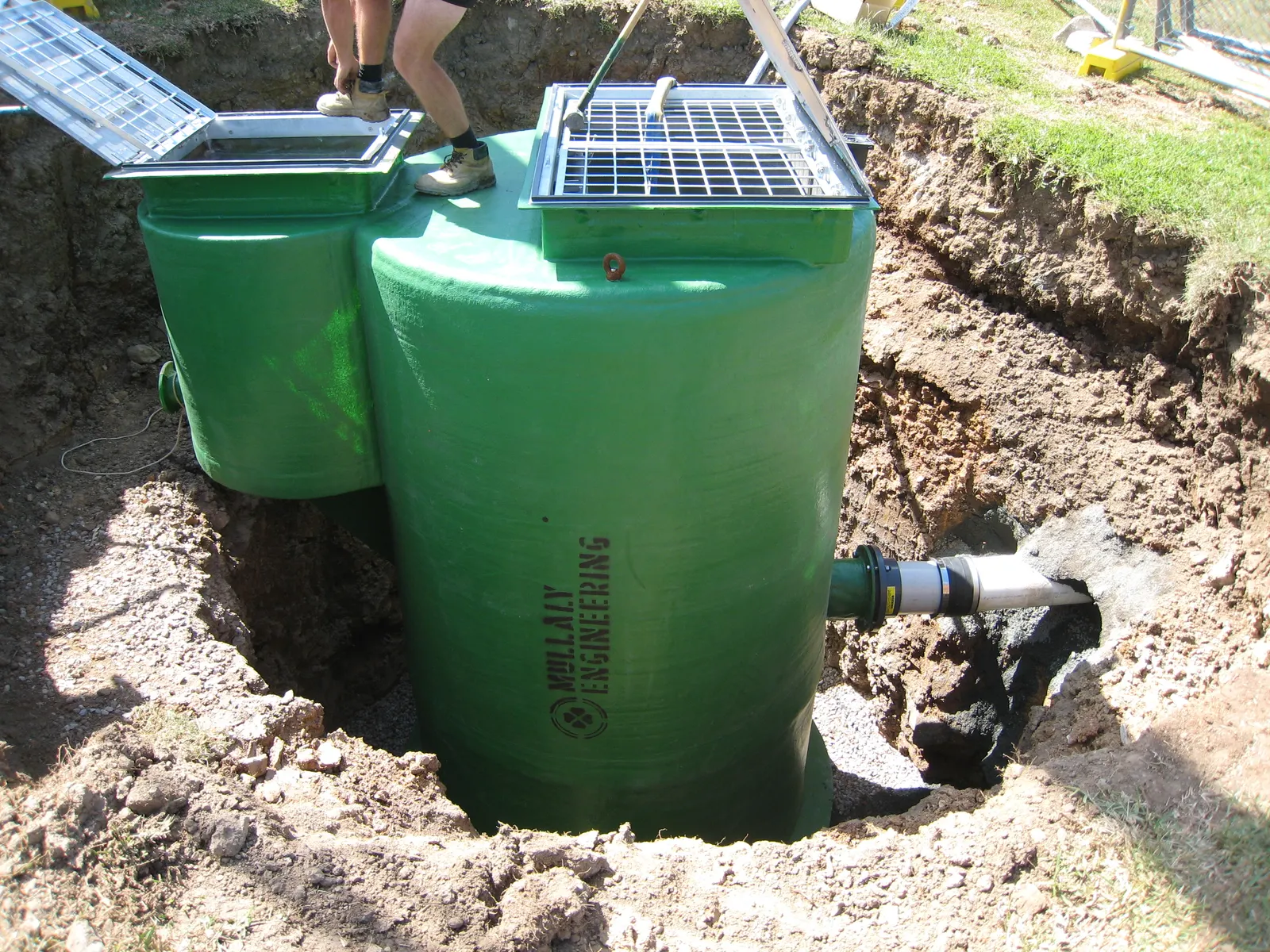 Mullaly-branded FRP wet well and valve pit combo sitting in its excavation with lids open and inlet pipe connected, Bingara Estate