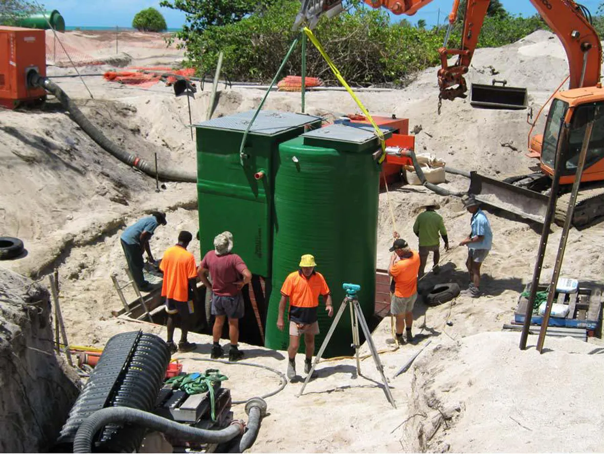 Local crew installing a Mullaly FRP wet well and valve pit combo in a sandy excavation on Warraber Island, Torres Strait