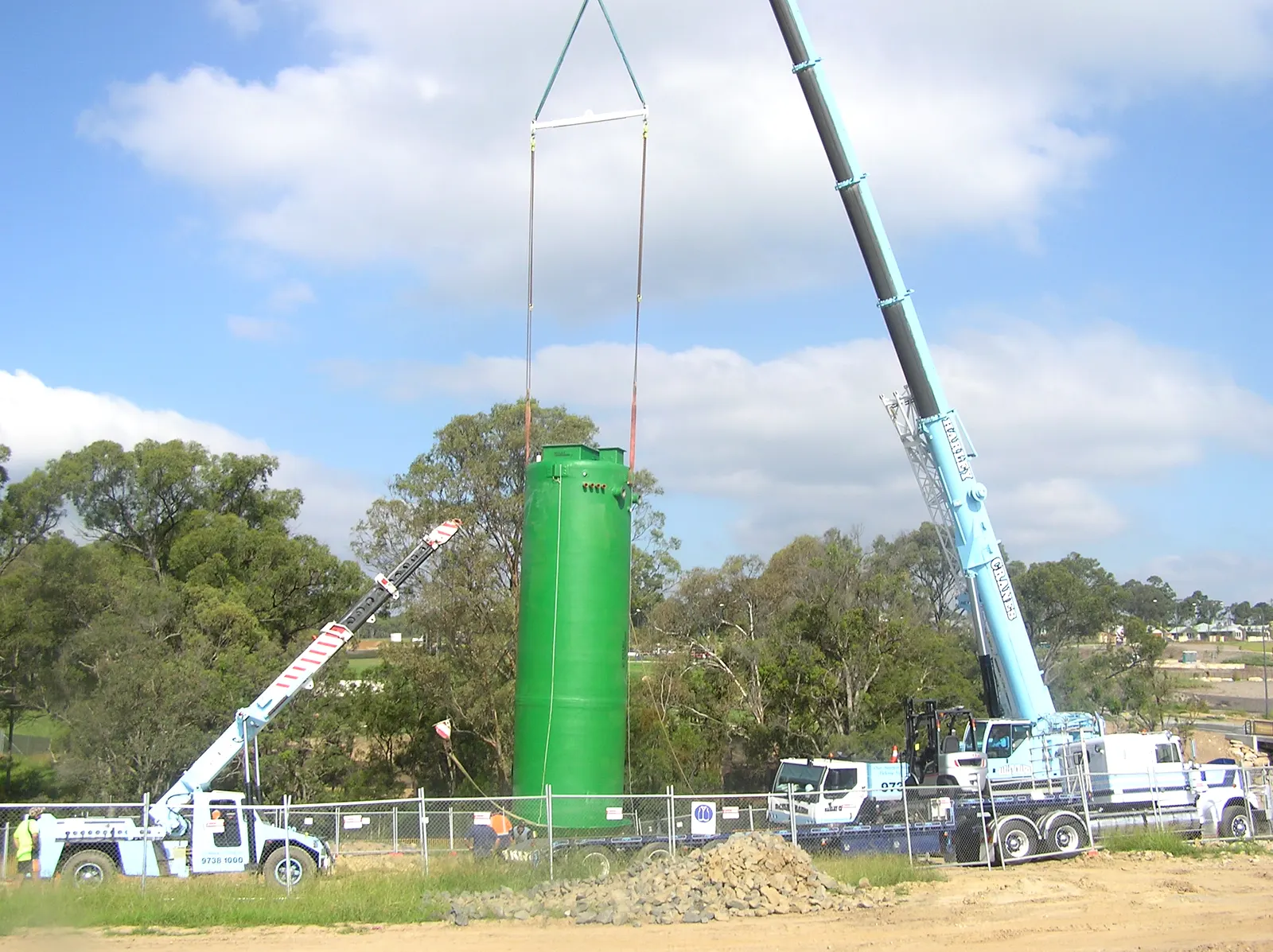 Mullaly green FRP wet well hanging upright from a mobile crane above the excavation at a Wilton pump station site, NSW