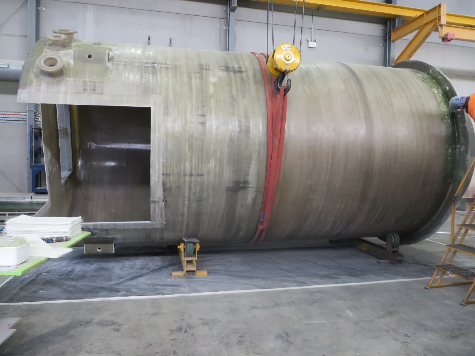 One-piece Mullaly fibreglass wet well shell on cradles in the factory before fit-out, with the valve chamber opening cut
