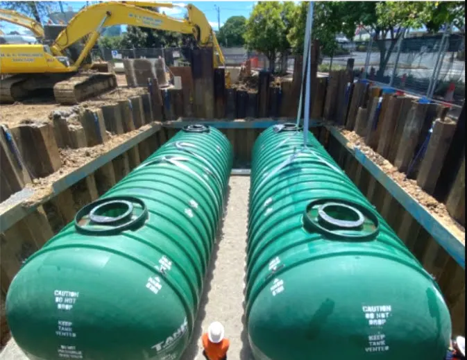 Two fibreglass water storage tanks set side by side in a shored excavation at Gympie